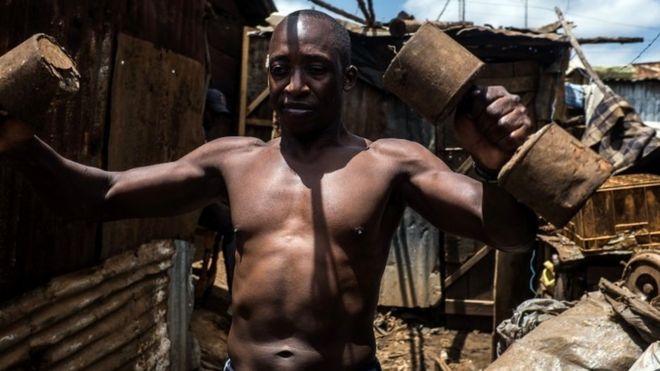 Johnstone Mainah does some daily workout routine with homemade weights in Kibera slum in Kenya