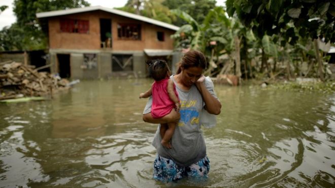Levelyn Alcoriza leaves her submerged house in Macapagal, north of Manila, on Wednesday, after a typhoon hit the area earlier in the week