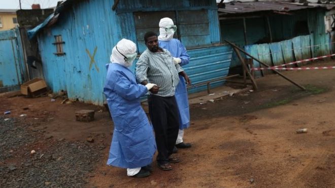 Health workers escort an Ebola survivor in Monrovia, Liberia. Photo: October 2014