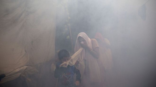 Residents cover their face and run in smoke as a municipal worker fumigates a residential area to prevent mosquitoes from breeding in New Delhi, India, Monday, Sept. 7, 2015