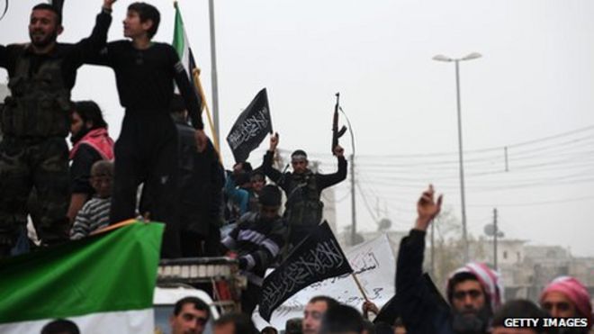 A Syrian rebel raises his weapon while waving an Islamist flag during an anti-regime protest in the northern city of Aleppo on March 22, 2013.