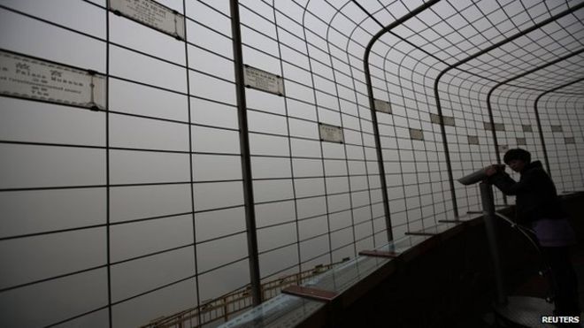 A visitor is silhouetted at an observatory tower during a polluted day in Beijing