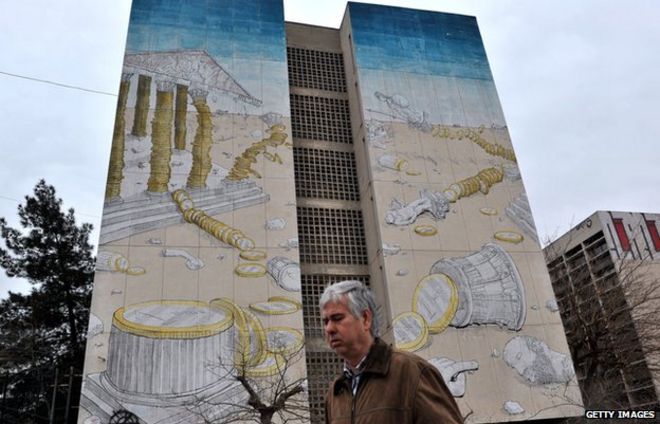 Man walks past graffiti of Acropolis collapsing in Thessaloniki (5 March)