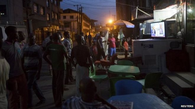 People watch election news coverage on television at a street in Lagos, Nigeria, 30 March 2015