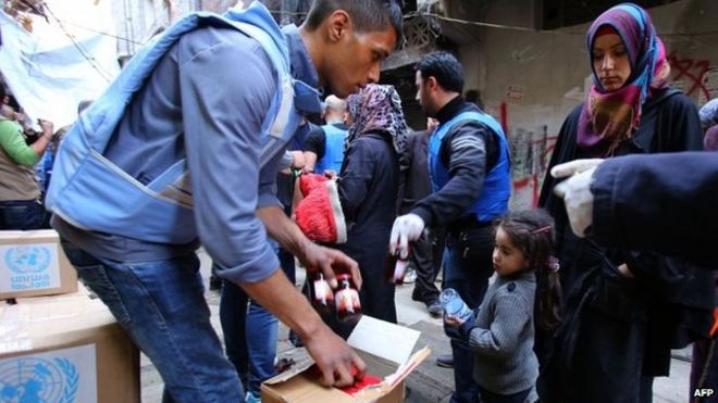 Palestinian refugees receive aid items distributed by the United Nations Relief and Works Agency for Palestine Refugees (UNRWA) at the Yarmouk refuge camp, south of Damascus, 10 March 2015
