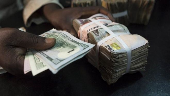 A trader changes dollars with naira at a currency exchange store in Lagos 12 February 2015