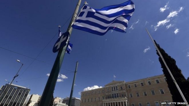 A greek flag flutters in front of the Greek parliament