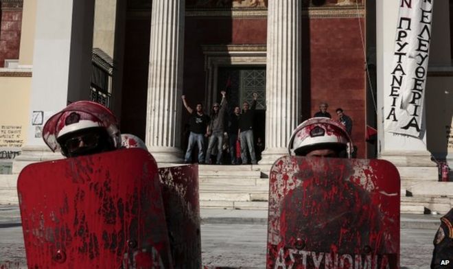 Protesters who have occupied the Athens University, shout from behind as police with their shields covered with red paint face-off against demonstrators during rally by their supporters, in Athens, Thursday, 16 April 2015.