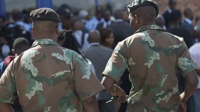 Two members of the South African Defence Force walk towards the Alexandra Police Station during a press conference by South Africa's Defence Minister, on 21 April 2015 in Alexandra Township, Johannesburg