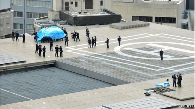 Police and security officers investigate an unidentified drone (L, under blue cover) which was found on the rooftop of Prime Minister Shinzo Abe's official residence in Tokyo, in this photo taken by Kyodo 22 April 2015