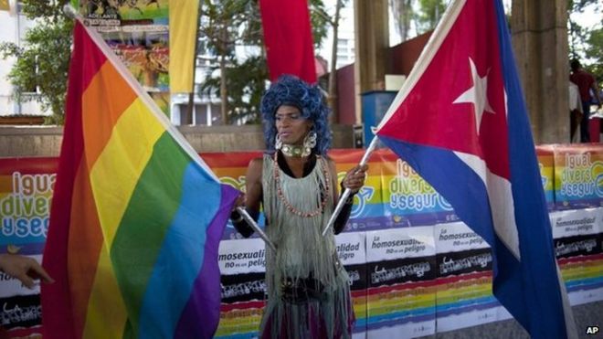 A transvestite holds a gay rights banner and a Cuban national flag at a march against homophobia in Havana on 11 May 2013