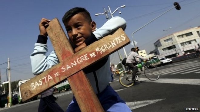 Ten-year-old Marco Carrasco, a migrant from Guatemala, stands outside the Basilica of the Virgin of Guadalupe while holding a cross during an annual human rights protest over Central American citizens crossing overland towards the United States, in Mexico City on 18 April 2015.