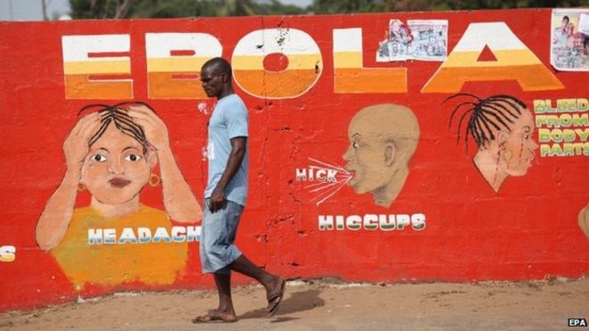 A Liberian man walking pass an ebola awareness painting on a wall in downtown Monrovia, Liberia