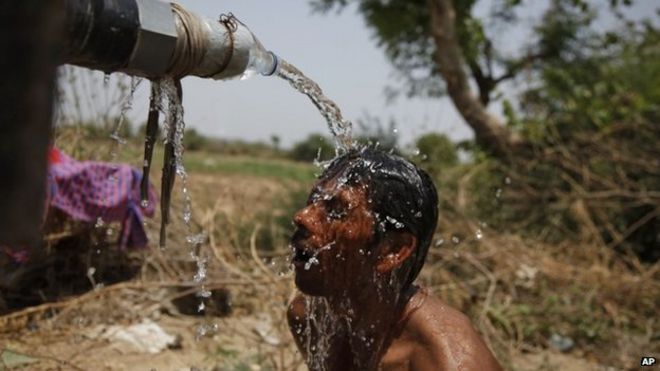 An Indian man takes bath under the tap of a water tanker on a hot day in Ahmadabad, India, Thursday, May 21, 2015