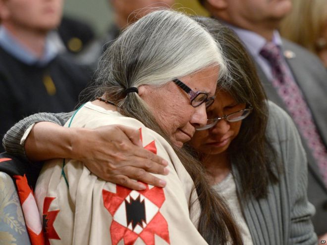 A woman is comforted in the audience during the closing ceremony of Commission