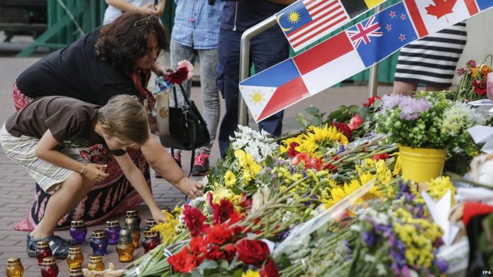 A woman and a young boy place flowers in commemoration of the victims of Malaysia Airlines MH17 plane accident in eastern Ukraine