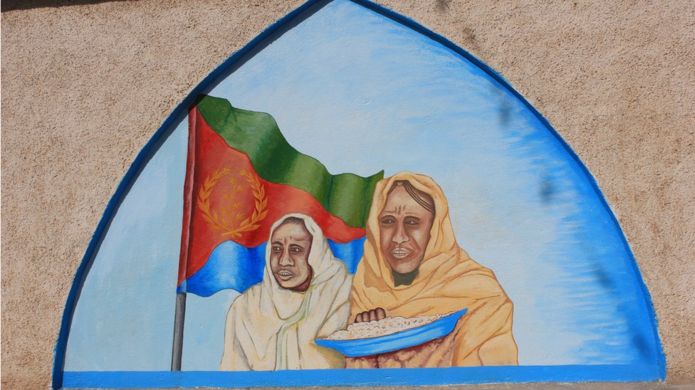 A mural in Eritrea showing two women with a bowl of food in front the Eritrean flag