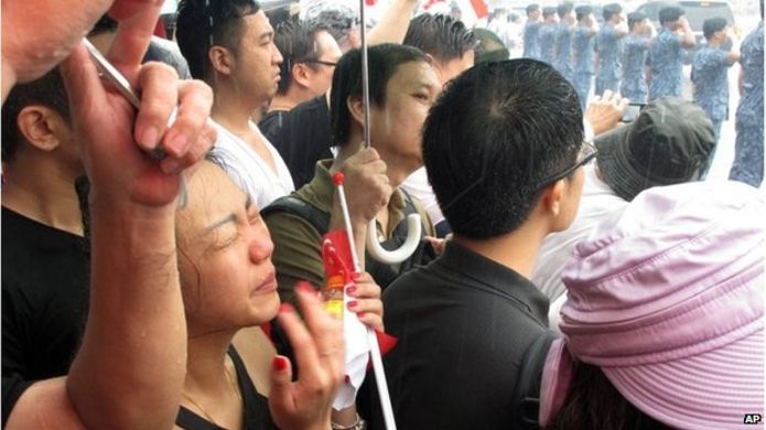 People in the rain watching funeral procession