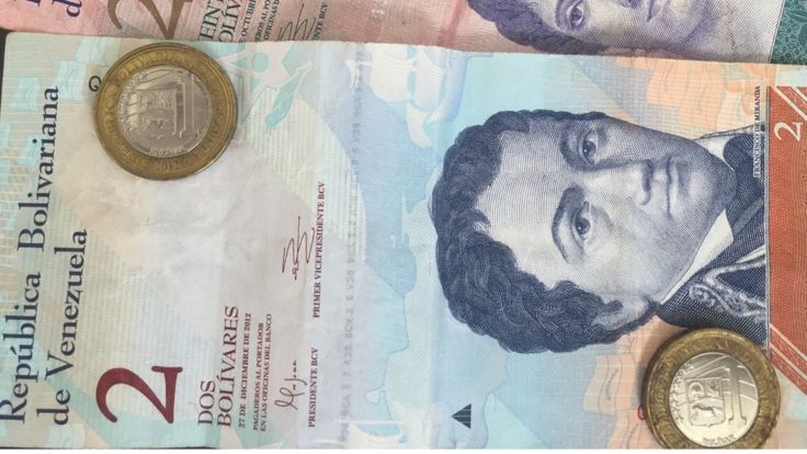 Un billete de 2 bolívares y dos monedas de uno.