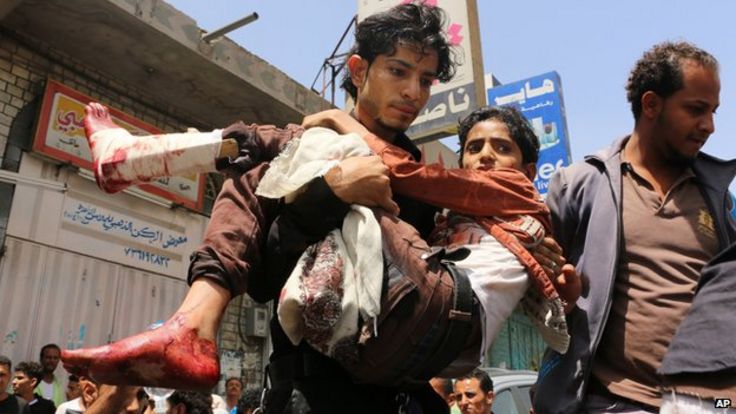 A man carries a boy who was injured during a crossfire between tribal fighters and Shiite militia known as Houthis, in Taiz, Yemen on 26 April 2015