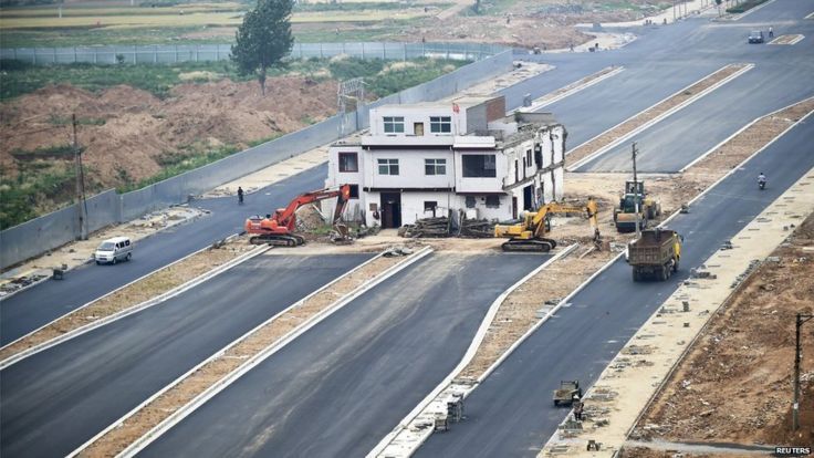 A three-storey nail house with a Chinese national flag on its rooftop is seen in the middle of a road in Luoyang