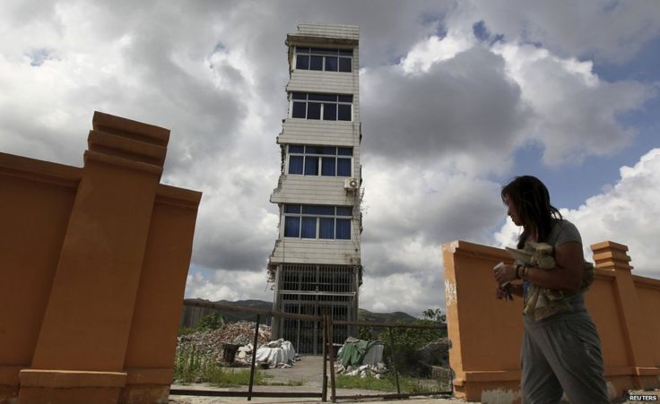 Zheng Meiju walks towards her partially demolished nail house in Rui'an, Zhejiang province