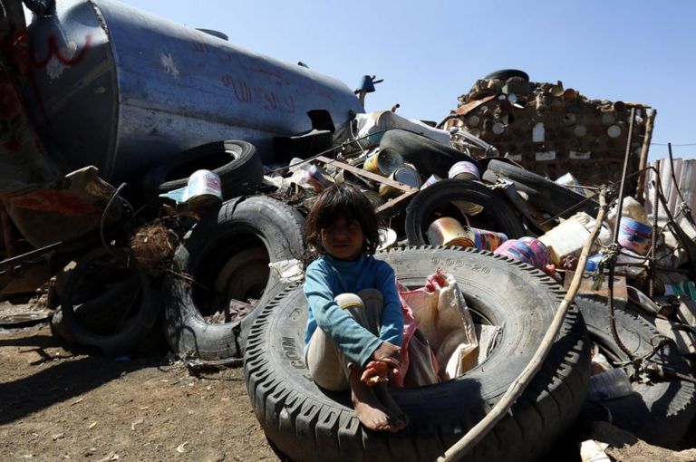 A small child sits on a scrapheap