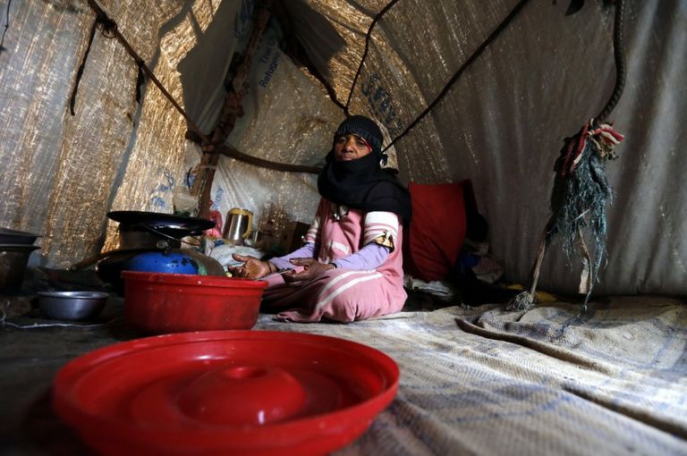 A woman sits on the floor of a makeshift house