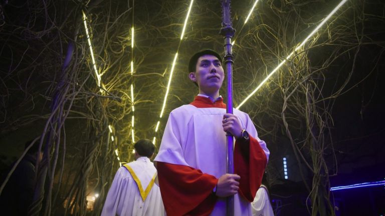 A cross-bearer prepares to enter the church as he attends the Christmas Eve mass at a Catholic church in Beijing on December 24, 2015