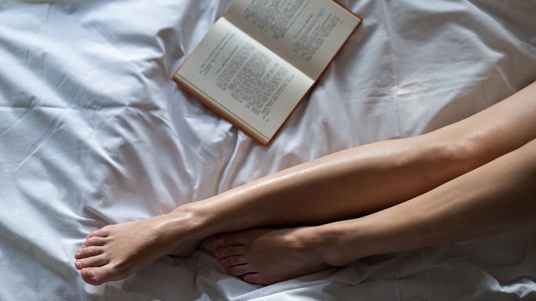 Legs and a book on a bed