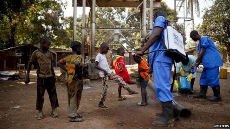 Children come forward to get their feet disinfected in Guinea
