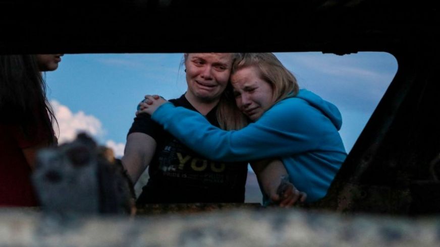 Miembros de la familia LeBarón lloran mientras miran el auto quemado donde al menos nueve personas fueron asesinados y quemados durante una emboscada de hombres armados en Bavispe, Sonora, el 5 de noviembre de 2019.