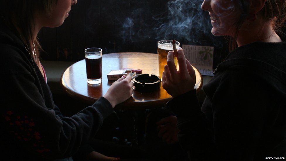 Smoking bans were introduced across the UK between 2006 and 2007. People smoking in a pub.