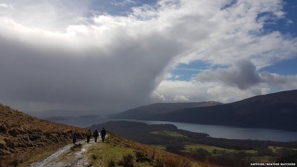 Clouds over country landscape. Some walkers can be seen the distance