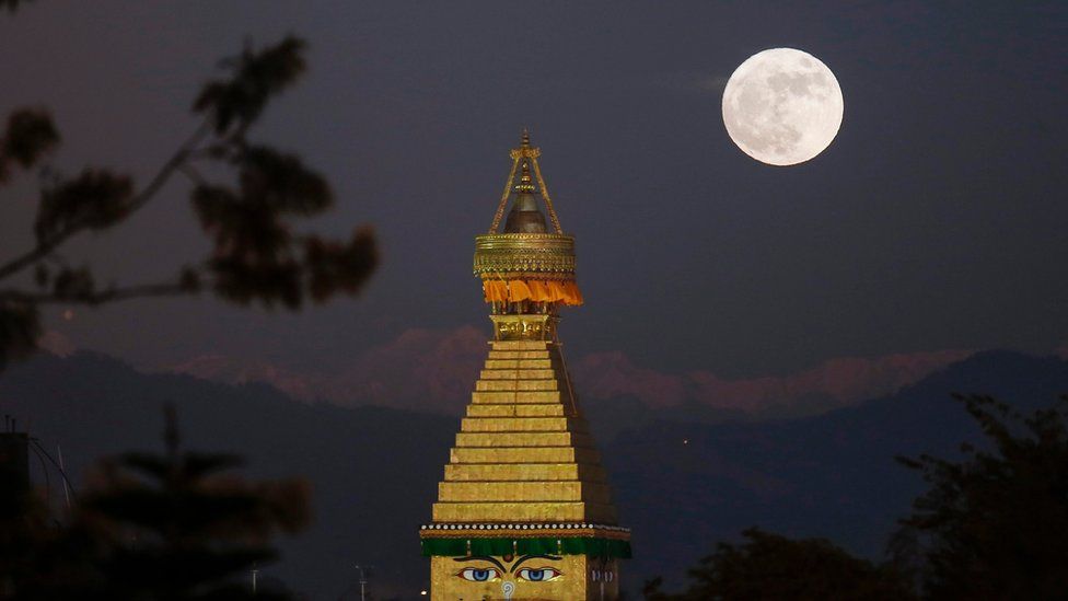 The moon rises over an upper portion of the Boudha stupa in Kathmandu, Nepal, 14 November 2016