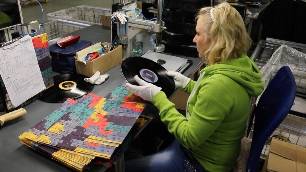 A vinyl record is quality checked in the packaging room