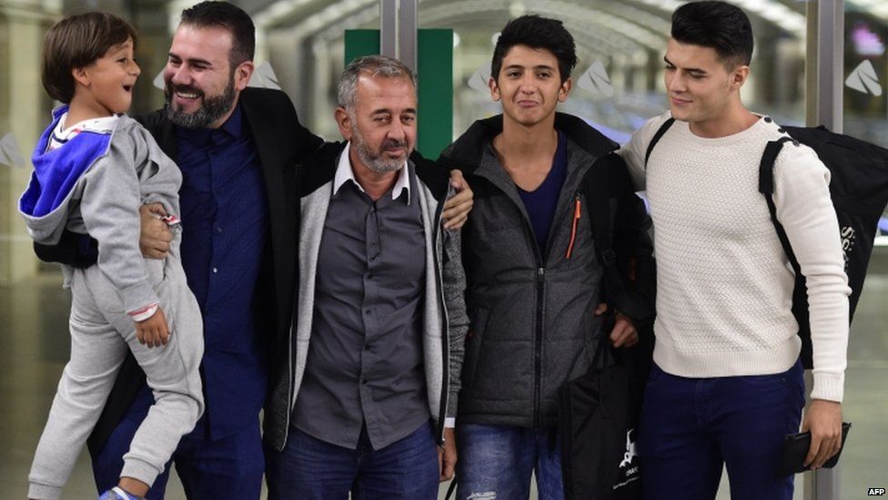 Osama Abdul Mohsen (3rd R), the Syrian refugee who made world headlines when a Hungarian journalist tripped him over as he fled, poses with his sons Zaid (L) and Mohamed (2nd R) and two representatives of the Spanish football coaching school CENAFE at Atocha train station in Madrid