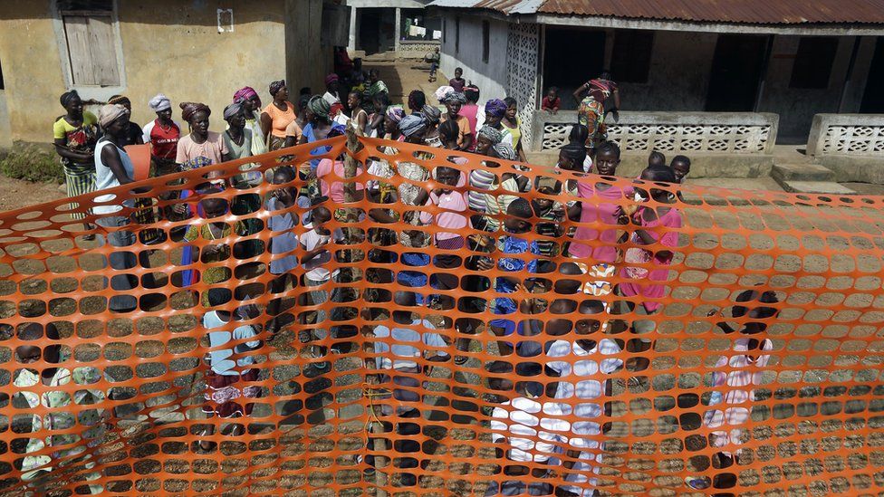 People wait to be released from Ebola quarantine in the village of Massessehbeh on the outskirts of Freetown, Sierra Leone on Aug. 14, 2015,