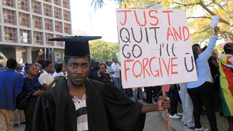 A protesters in Harare, Zimbabwe, dressed in a graduation gown and cap holding a sign reading "Just Quit And Go I'll Fogive U" - Wednesday 3 August 2016