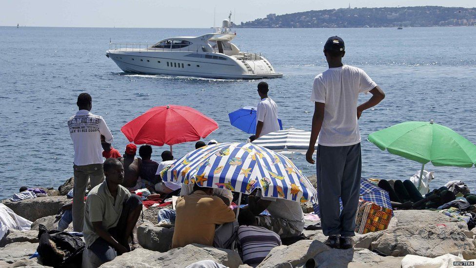 People sitting under umbrellas looking at a boat