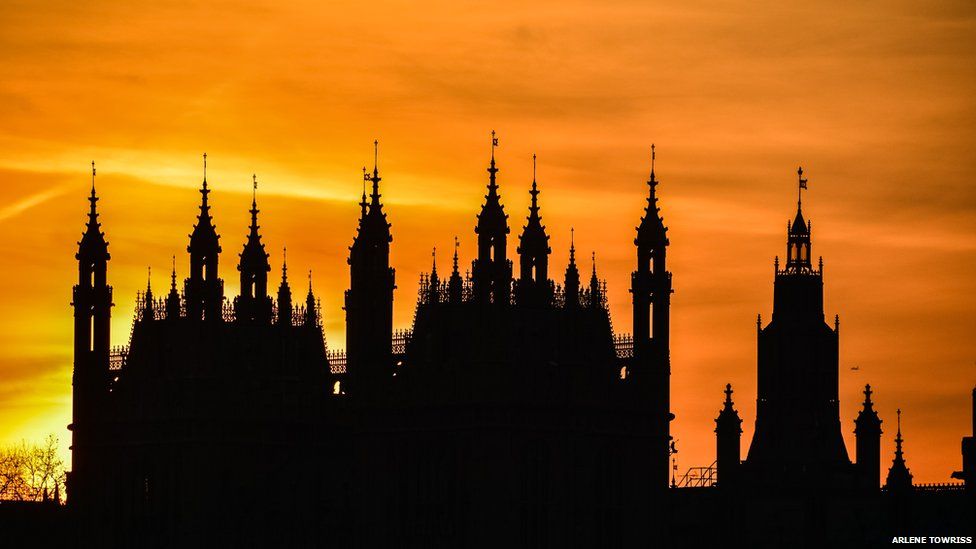 A cathedral's spires are silhouetted against a yellow sunset