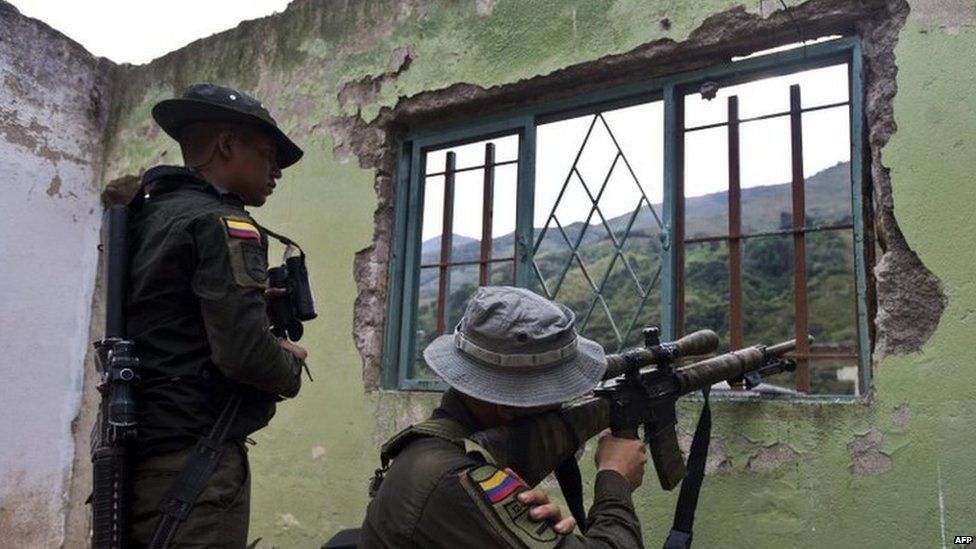 Colombian police point their guns at the mountains at a house destroyed by the Farc in Cauca