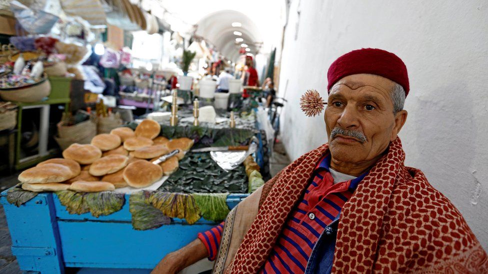 A street vendor poses with a machmoum, a bouquet of jasmine, behind his ear at the Kasbah souk in the old town of Tunis, Tunisia