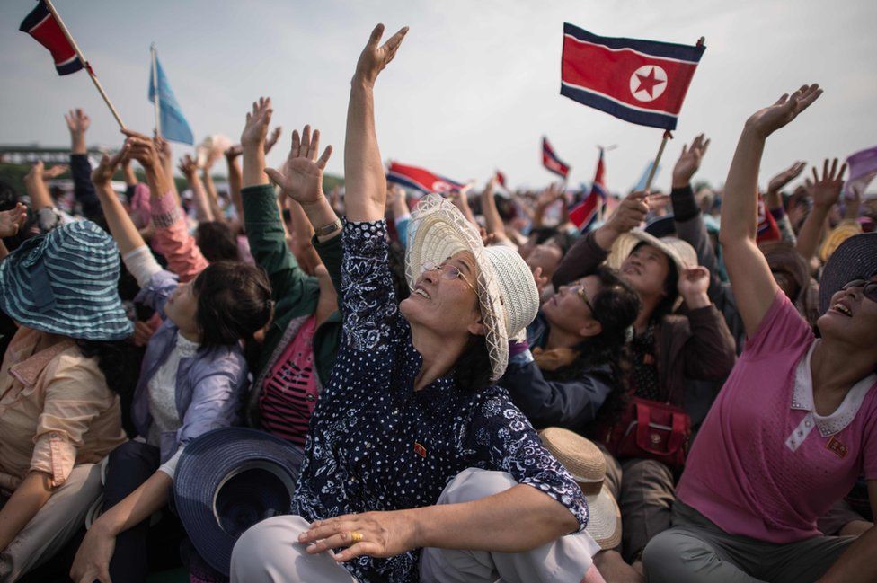 வானில் மிதந்தபடி வான்குடை (பாரசூட்) மூலம் நிகழ்த்தப்பட்ட சாகசங்களை பார்த்து ஆரவாரிக்கும் பார்வையாளர்கள்.