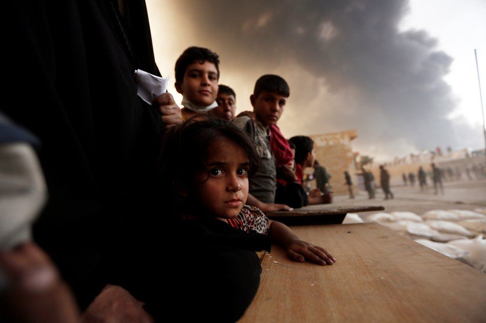 Gente a la espera de suministros de comida en un centro de asistencia para desplazados en el sur de Mosul, Irak, 21 de octubre, 2016.