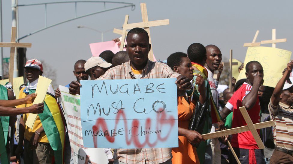 Protesters in Harare, Zimbabwe, one holding a "Mugabe must go" sign and others holding wooden crosses - Wednesday 3 August 2016