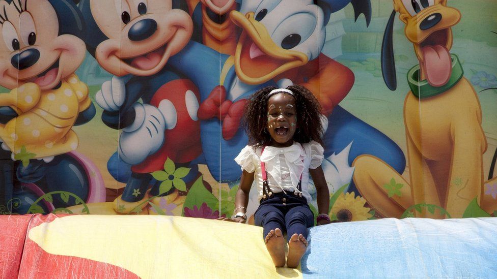 நைரோபியின் தலைநகரிலுள்ள பூங்காவில் புத்தாண்டை கொண்டாட குடும்பங்கள் கூடியுள்ள நிலையில், சறுக்கி விளையாடும் கென்ய குழந்தை