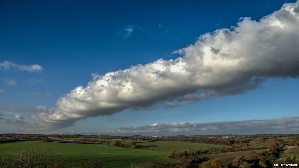 A line of white fluffy cloud in countryside on a bright day