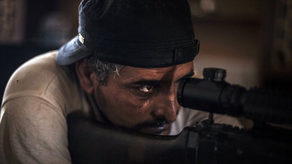 A fighter from forces affiliated to the Tripoli government scans for targets from his position in a building at the frontline in Sirte, Libya - Wednesday 28 September 2016