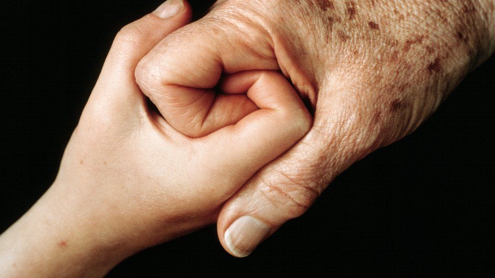 A young hand clasping and older hand